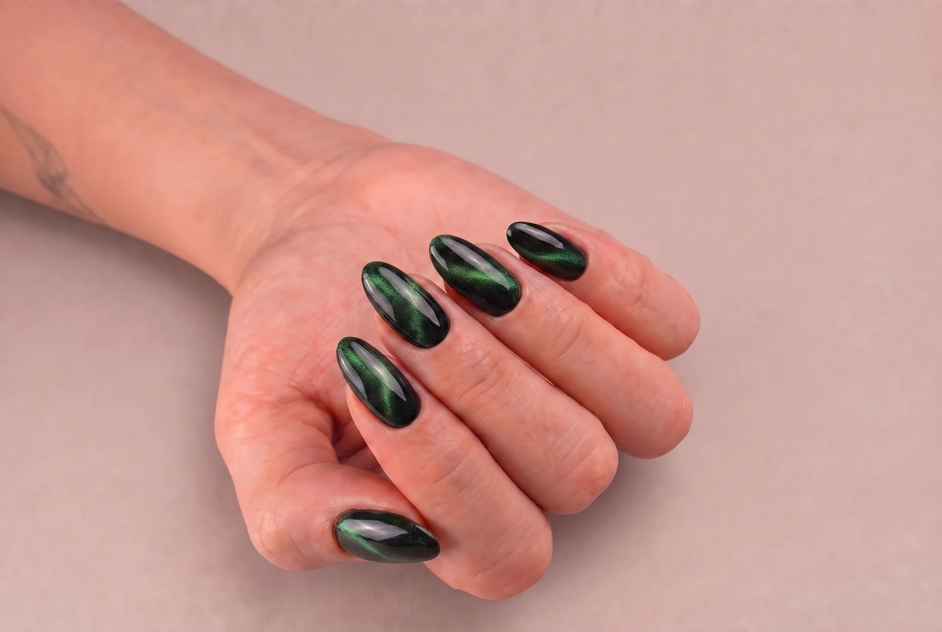 Uñas almendradas en verde oscuro con efecto imán